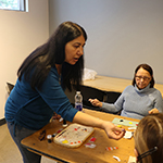 A woman teaching a group of visitors on beading techniques.