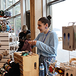 A craftswoman chatting with visitors behind her kiosk.
