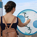 A young woman explores the Putep 't-awt site, engaging with interactive panels on Wolastoqiyik Wahsipekuk First Nation history.